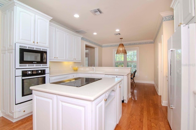 kitchen with black appliances, hanging light fixtures, light hardwood / wood-style flooring, ornamental molding, and white cabinetry