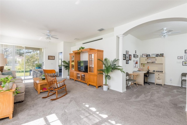 carpeted living room with ornate columns and ceiling fan