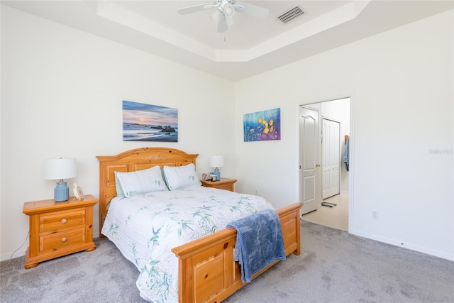 carpeted bedroom with ceiling fan and a raised ceiling