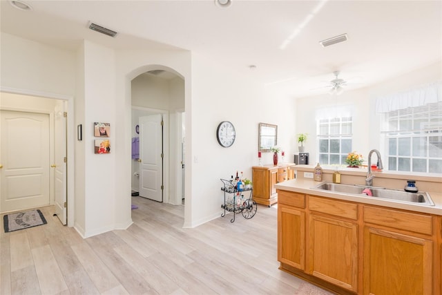 kitchen with ceiling fan, light wood-type flooring, and sink