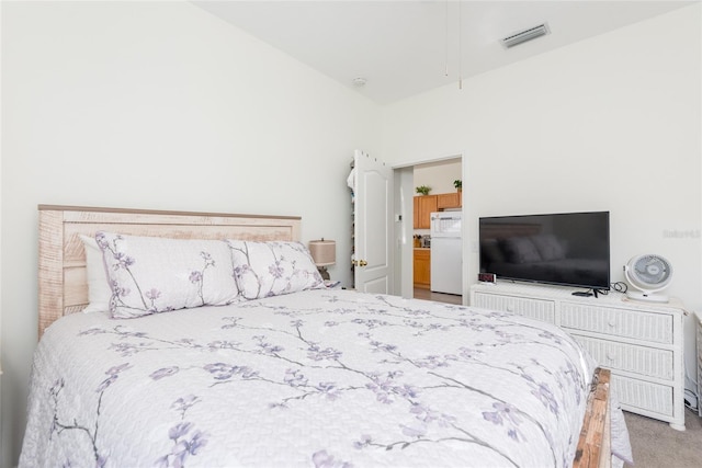 bedroom featuring lofted ceiling, white fridge, and light colored carpet