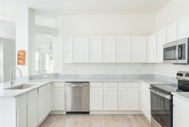 5733 Heronpark Pl, Lithia, FL 33547 - kitchen featuring appliances with stainless steel finishes, a peninsula, light stone counters, white cabinetry, and a ceiling fan