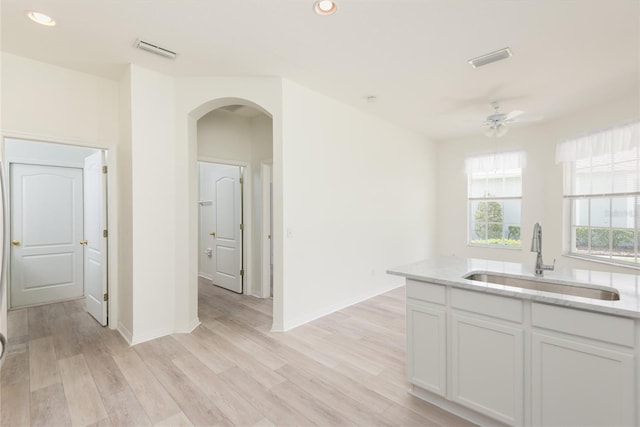 5733 Heronpark Pl, Lithia, FL 33547 - kitchen featuring arched walkways, light stone countertops, white cabinets, ceiling fan, and recessed lighting