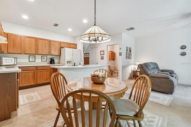 dining space with ceiling fan and light colored carpet