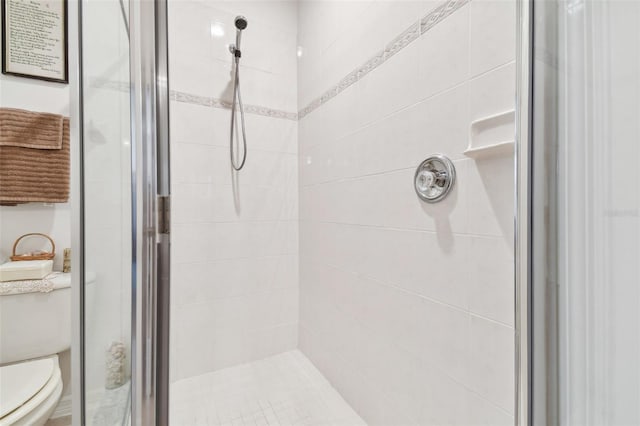 bathroom with a shower with door and toilet