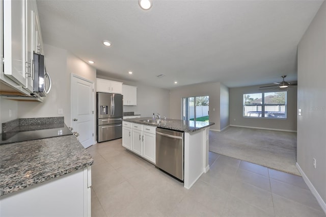 kitchen with white cabinets, light colored carpet, stainless steel appliances, and a center island with sink