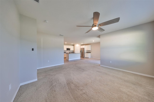 unfurnished living room featuring light colored carpet and ceiling fan