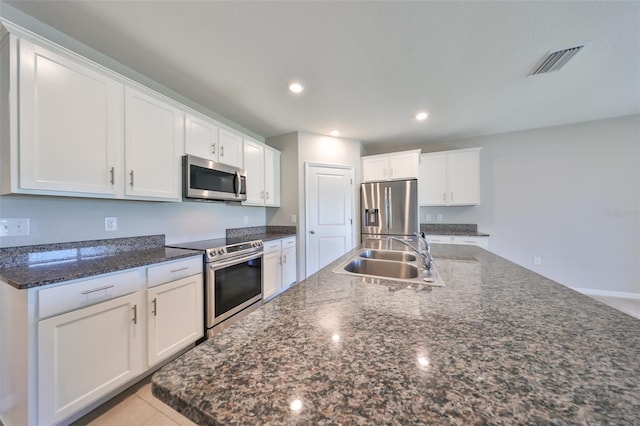 kitchen featuring a kitchen island with sink, sink, light tile patterned floors, appliances with stainless steel finishes, and white cabinetry