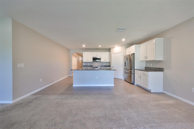 kitchen with white cabinets, light colored carpet, a kitchen island with sink, and appliances with stainless steel finishes