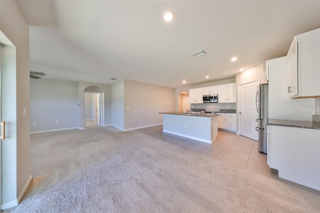 kitchen featuring a kitchen island with sink, white cabinets, light colored carpet, and appliances with stainless steel finishes