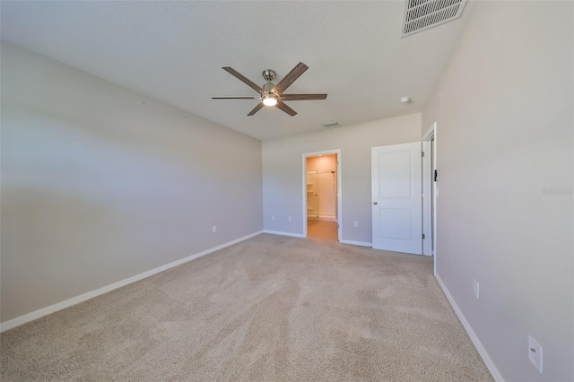 unfurnished bedroom featuring ceiling fan, light carpet, and a textured ceiling