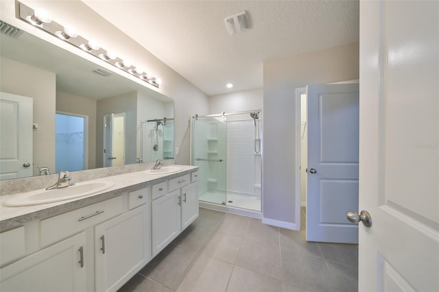 bathroom featuring vanity, a textured ceiling, tile patterned floors, and an enclosed shower