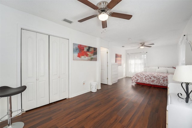 bedroom featuring a textured ceiling, dark hardwood / wood-style flooring, a closet, and ceiling fan