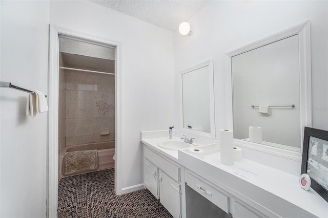 bathroom with tile patterned flooring, vanity, a textured ceiling, and tiled shower / bath