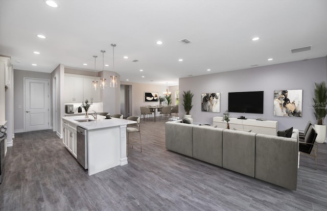 kitchen featuring white cabinetry, dishwasher, hanging light fixtures, dark hardwood / wood-style floors, and a kitchen island with sink