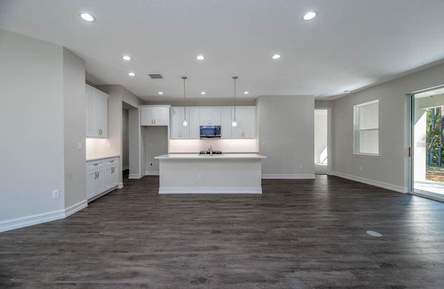 interior space with dark hardwood / wood-style flooring, white cabinets, and an island with sink