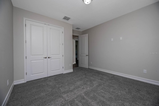 unfurnished bedroom featuring dark carpet and a closet