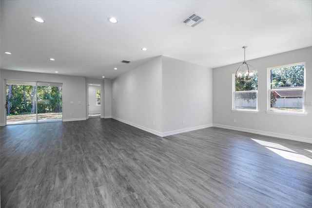 unfurnished living room featuring dark hardwood / wood-style flooring and a chandelier