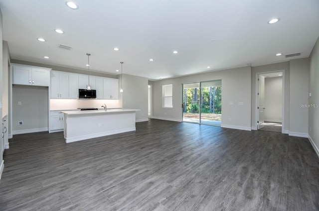 kitchen featuring dark hardwood / wood-style flooring, sink, decorative light fixtures, white cabinets, and an island with sink