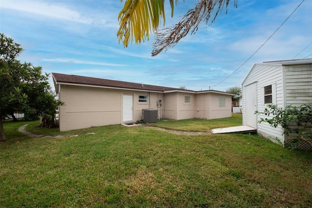 rear view of property with a yard and central air condition unit