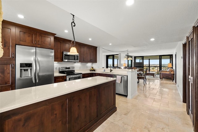 kitchen with sink, a notable chandelier, kitchen peninsula, decorative light fixtures, and appliances with stainless steel finishes