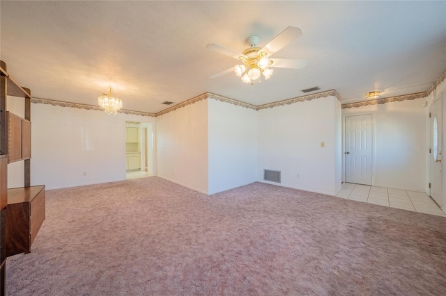 carpeted empty room featuring ceiling fan with notable chandelier and ornamental molding