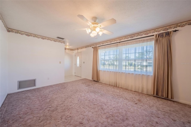 spare room featuring a textured ceiling, light colored carpet, and ceiling fan