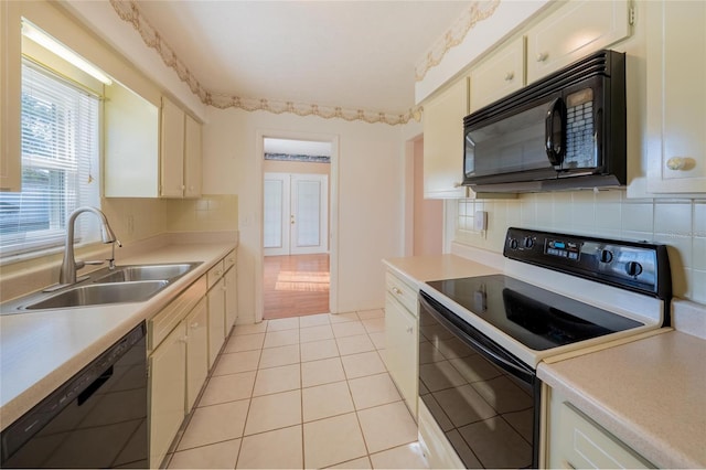 kitchen featuring black appliances, decorative backsplash, light tile patterned floors, and sink