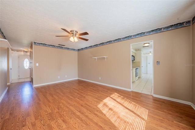 unfurnished room with a textured ceiling, light hardwood / wood-style flooring, and ceiling fan