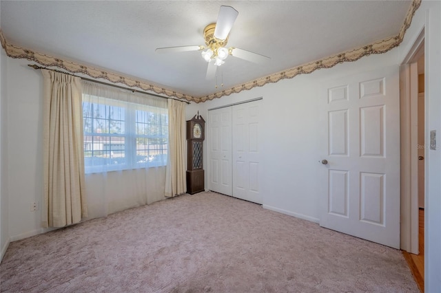 unfurnished bedroom with ceiling fan, a closet, and light colored carpet