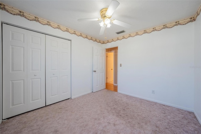 unfurnished bedroom with a closet, light colored carpet, and ceiling fan