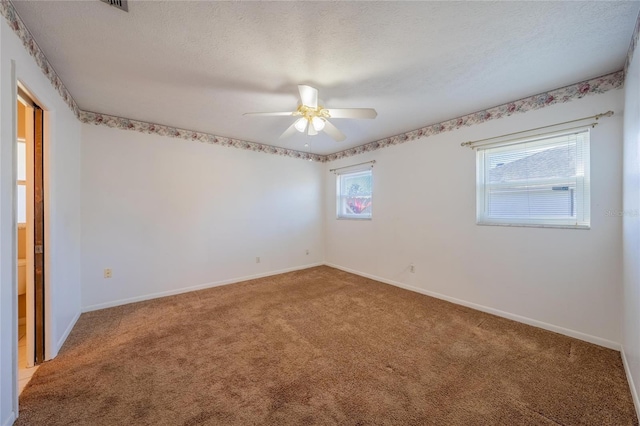 carpeted spare room featuring ceiling fan and a textured ceiling