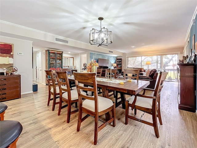 dining room with an inviting chandelier, light hardwood / wood-style flooring, and ornamental molding