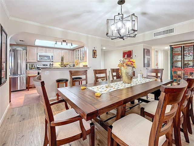 dining area with light wood-type flooring, an inviting chandelier, and ornamental molding