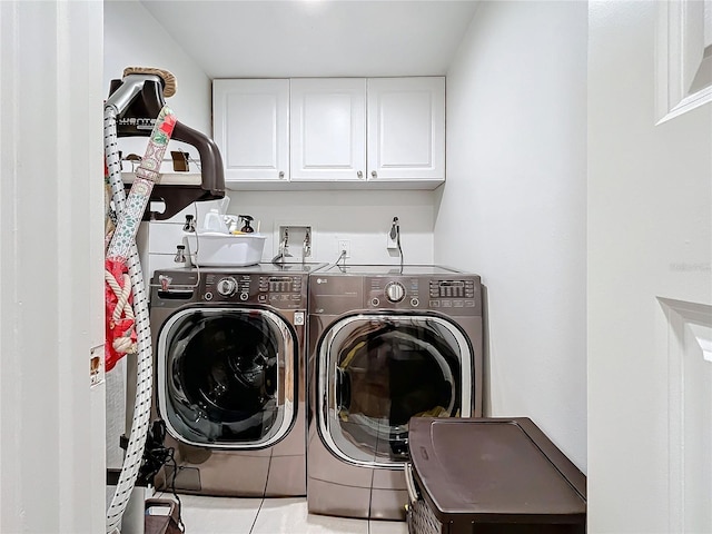 clothes washing area with cabinets, tile patterned flooring, and washer and dryer