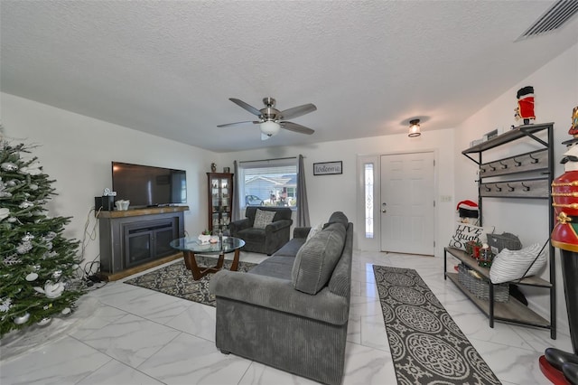 living room with ceiling fan and a textured ceiling