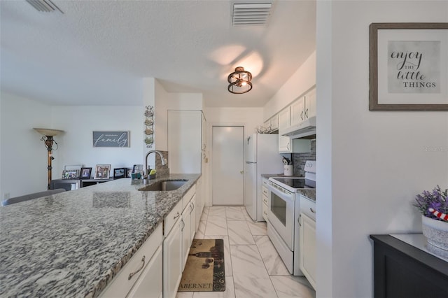 kitchen featuring white appliances, dark stone counters, white cabinets, sink, and a textured ceiling