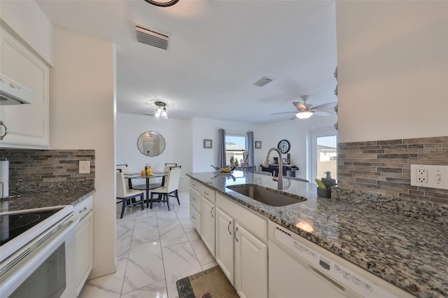 kitchen featuring white appliances, dark stone counters, white cabinets, sink, and tasteful backsplash