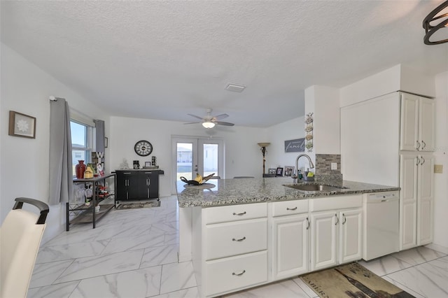 kitchen with sink, french doors, kitchen peninsula, white dishwasher, and white cabinets