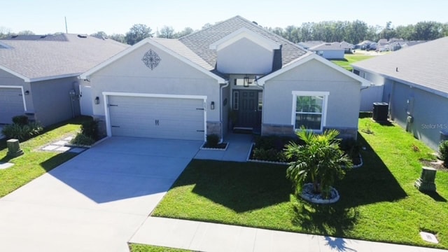 view of front of house featuring central AC, a front yard, and a garage