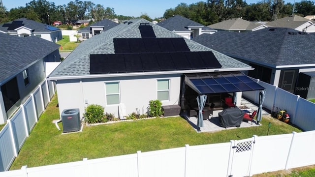 rear view of house featuring solar panels, a yard, a patio, and central AC unit