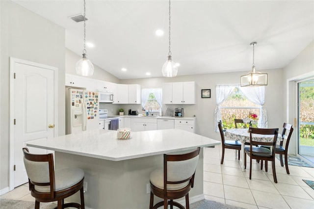 kitchen featuring lofted ceiling, white cabinetry, a kitchen island, and white appliances