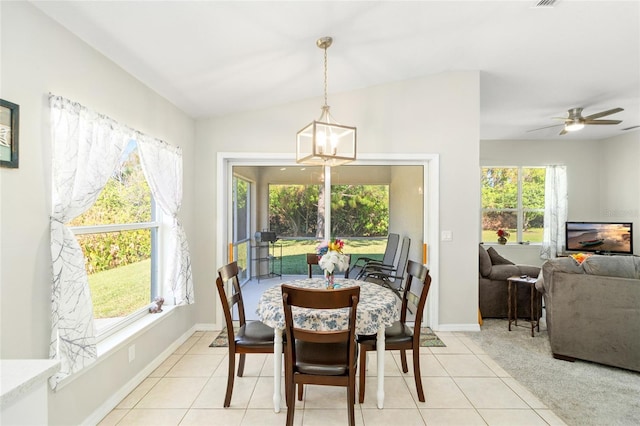 dining area featuring lofted ceiling, light tile patterned flooring, and ceiling fan with notable chandelier