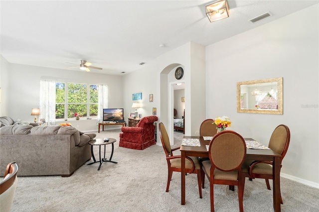 dining space with ceiling fan and light carpet