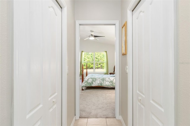 hallway with light colored carpet and vaulted ceiling