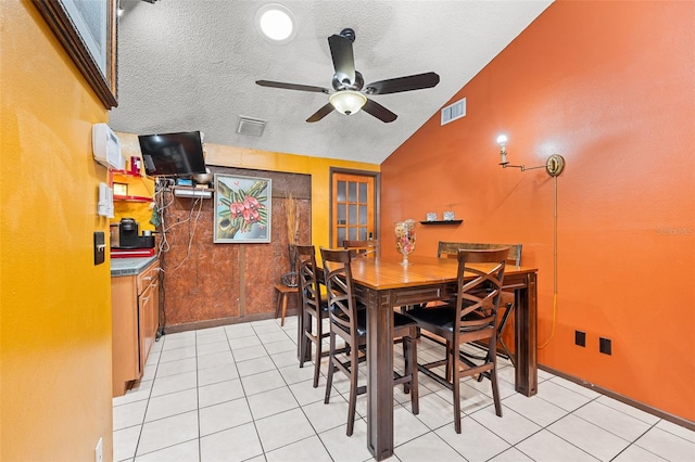 tiled dining area with a textured ceiling, vaulted ceiling, and ceiling fan