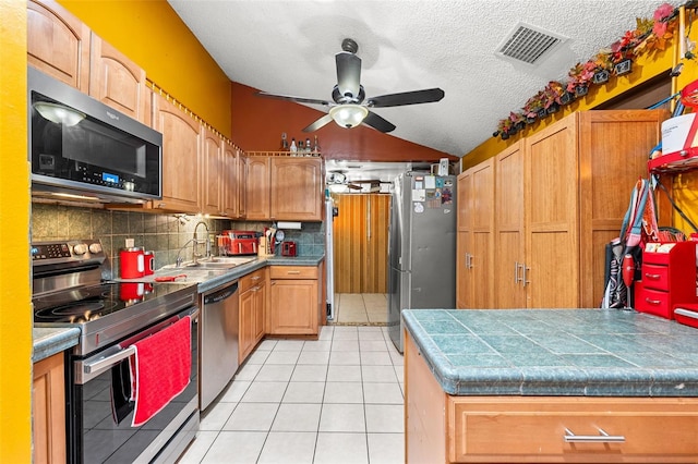 kitchen with ceiling fan, sink, a textured ceiling, light tile patterned flooring, and appliances with stainless steel finishes