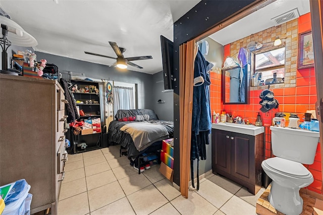 tiled bedroom featuring sink, ceiling fan, and tile walls