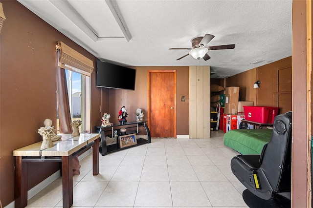 living room with ceiling fan, light tile patterned flooring, and a textured ceiling