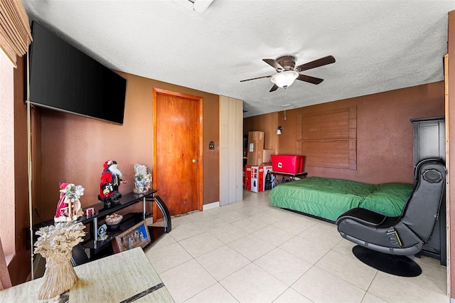 tiled bedroom with ceiling fan and a textured ceiling